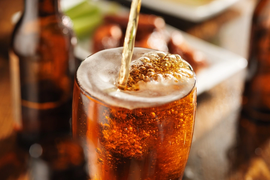Cola drink with ice and straw in glass at dining table with food