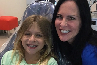 Woman and young girl smiling together at Statler Orthodontics office in casual setting.