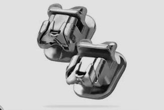 Metallic orthodontic brackets displayed against neutral gray background for dental treatment.