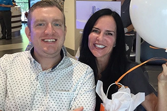 Two people smiling at camera at Statler Orthodontics indoor event or gathering.