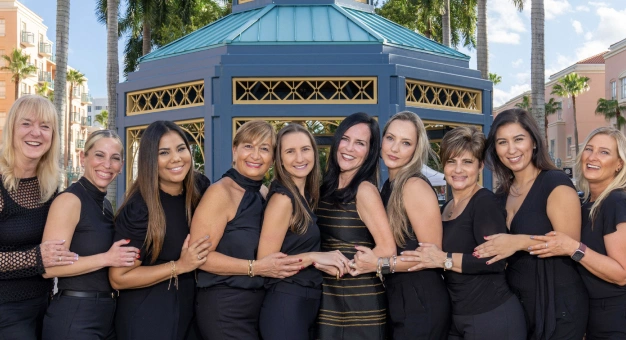 Team of female orthodontic professionals in black uniforms posing together outdoors at Statler Orthodontics office.