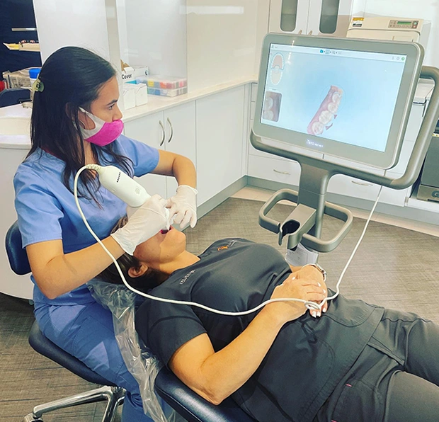 Orthodontist examines patient's teeth using digital scanner in modern dental office.