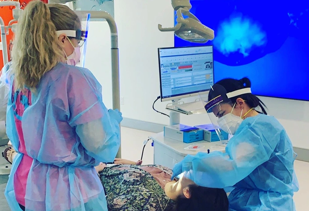 Orthodontist examining young patient's teeth in modern dental office with digital displays.