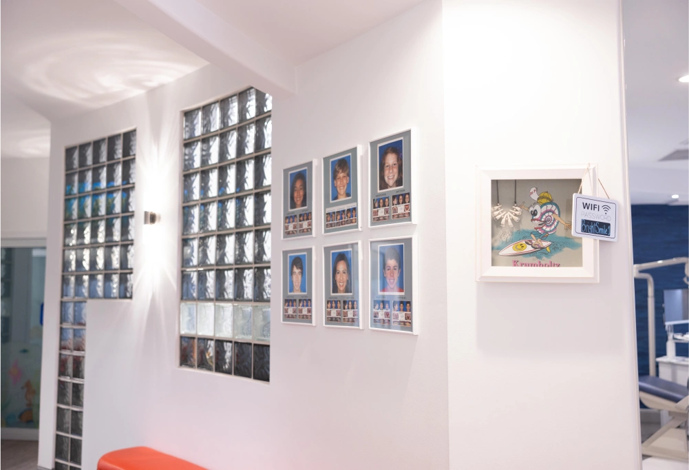 Orthodontics office interior with shelving, framed certificates, and bright white walls displaying professional credentials.