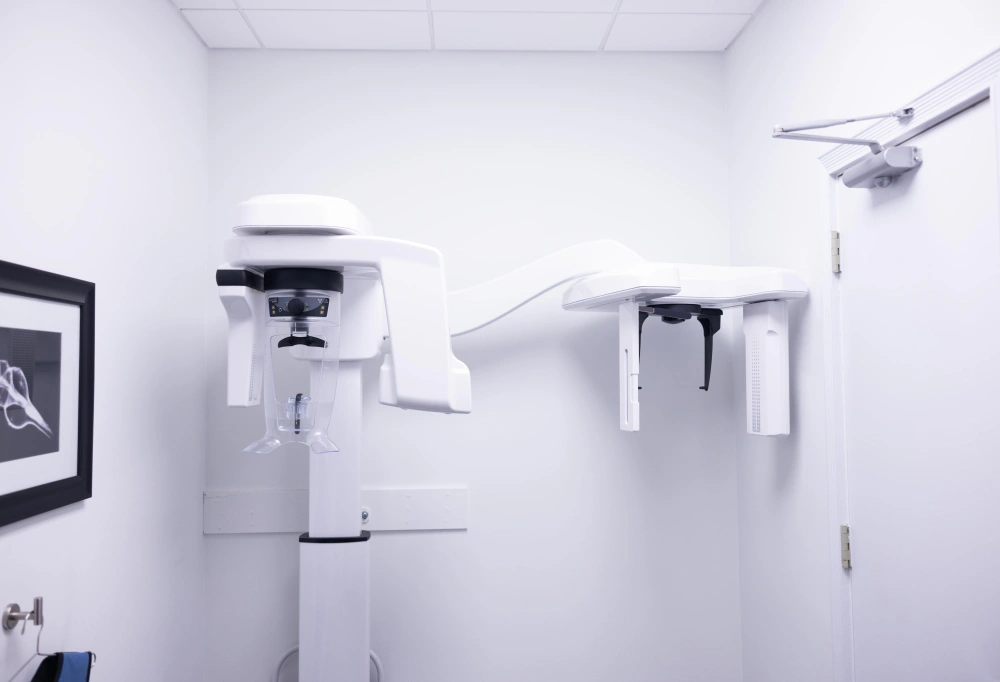 Modern orthodontic treatment room with dental X-ray equipment and white clinical furnishings.