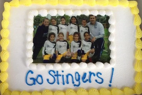 Team photo cake decorated with "Go Stingers!" text in blue icing.