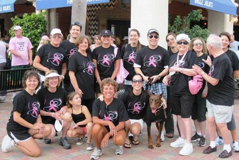 Large group wearing matching black t-shirts posing together outdoors at community event.