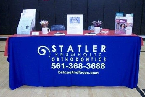 Statler Orthodontics trade show booth with blue tablecloth displaying orthodontic products and materials.