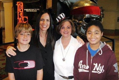 Four smiling people posing together indoors at what appears to be an orthodontics office or event.