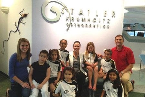 Group of children and adults posing together in Statler Orthodontics office setting.