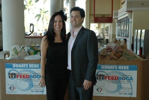 Two people stand together indoors near donation boxes for a charitable organization.