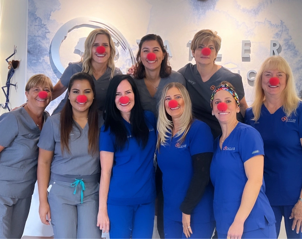 Statler Orthodontics team members wearing blue uniforms posing together in modern office setting