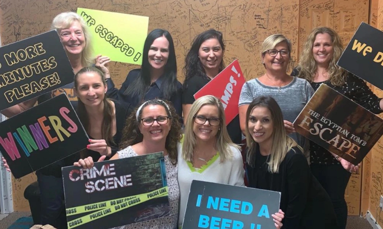 Statler Orthodontics team members posing together indoors with promotional signs and banners.
