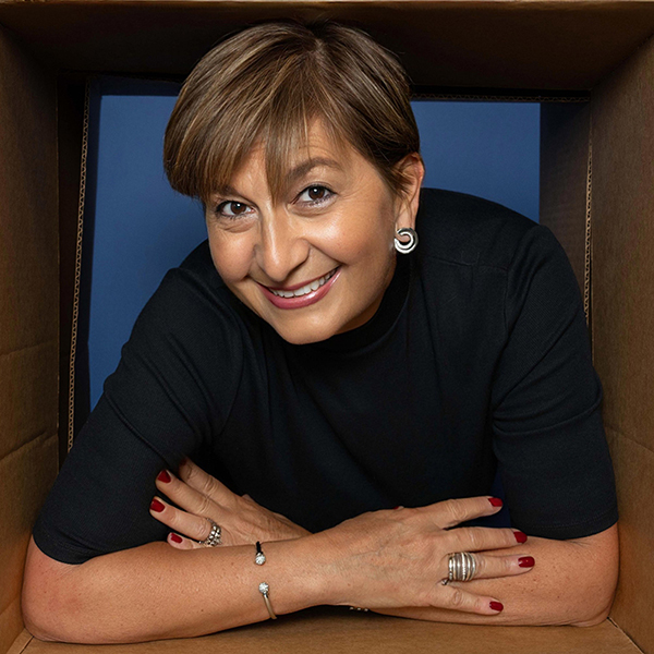 Professional woman smiling at camera, arms crossed, wearing black shirt against blue background.
