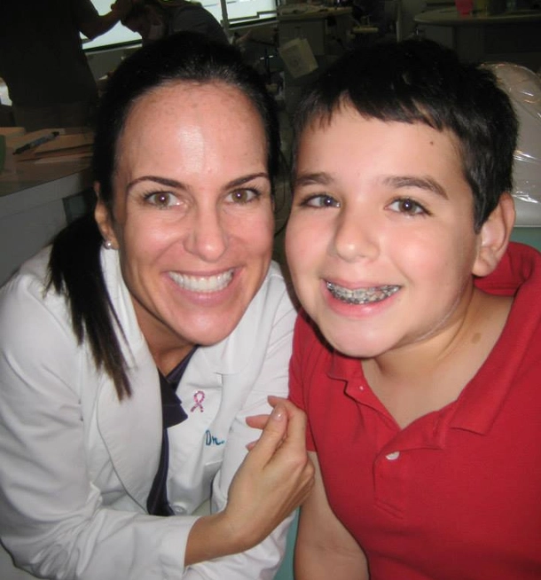 Woman and young boy smiling together indoors at orthodontics office setting.