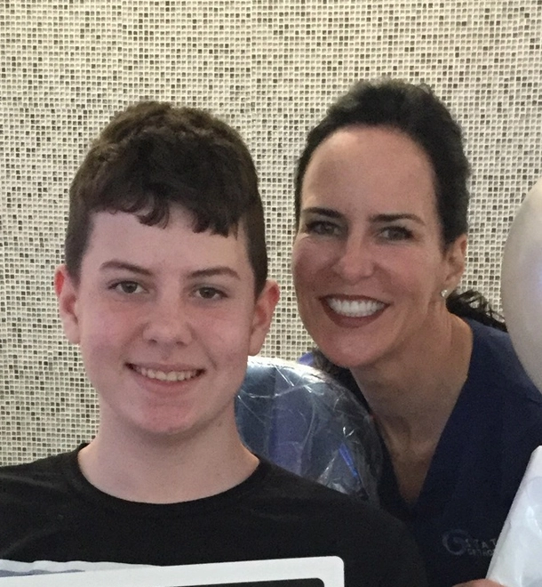 Woman and young boy smiling together at Statler Orthodontics against tiled background.