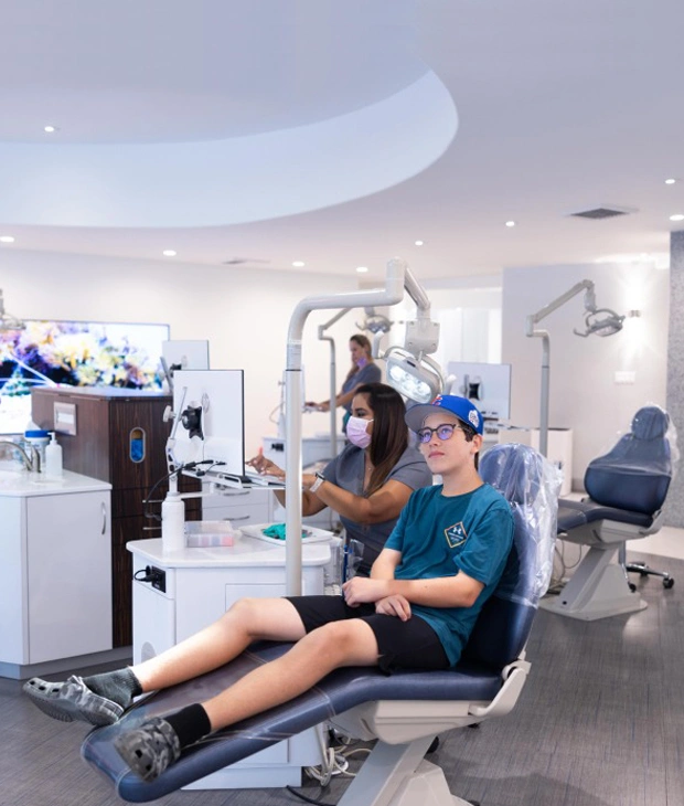 Patient receiving orthodontic treatment in modern dental office with dental professional assisting.