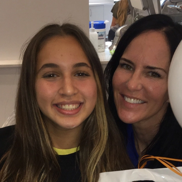Two smiling females posing together indoors at Statler Orthodontics office setting.